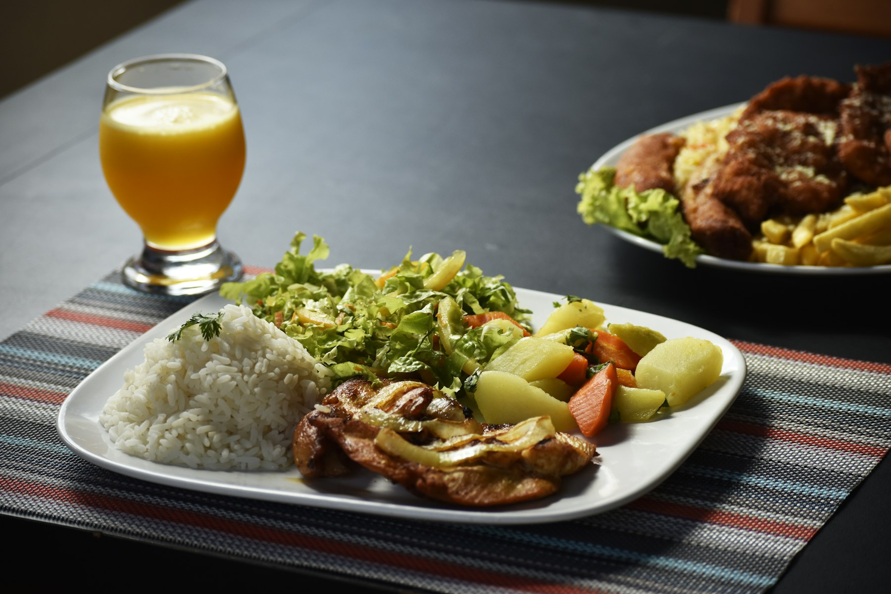 Plate of rice, curry and salad with a fresh juice
