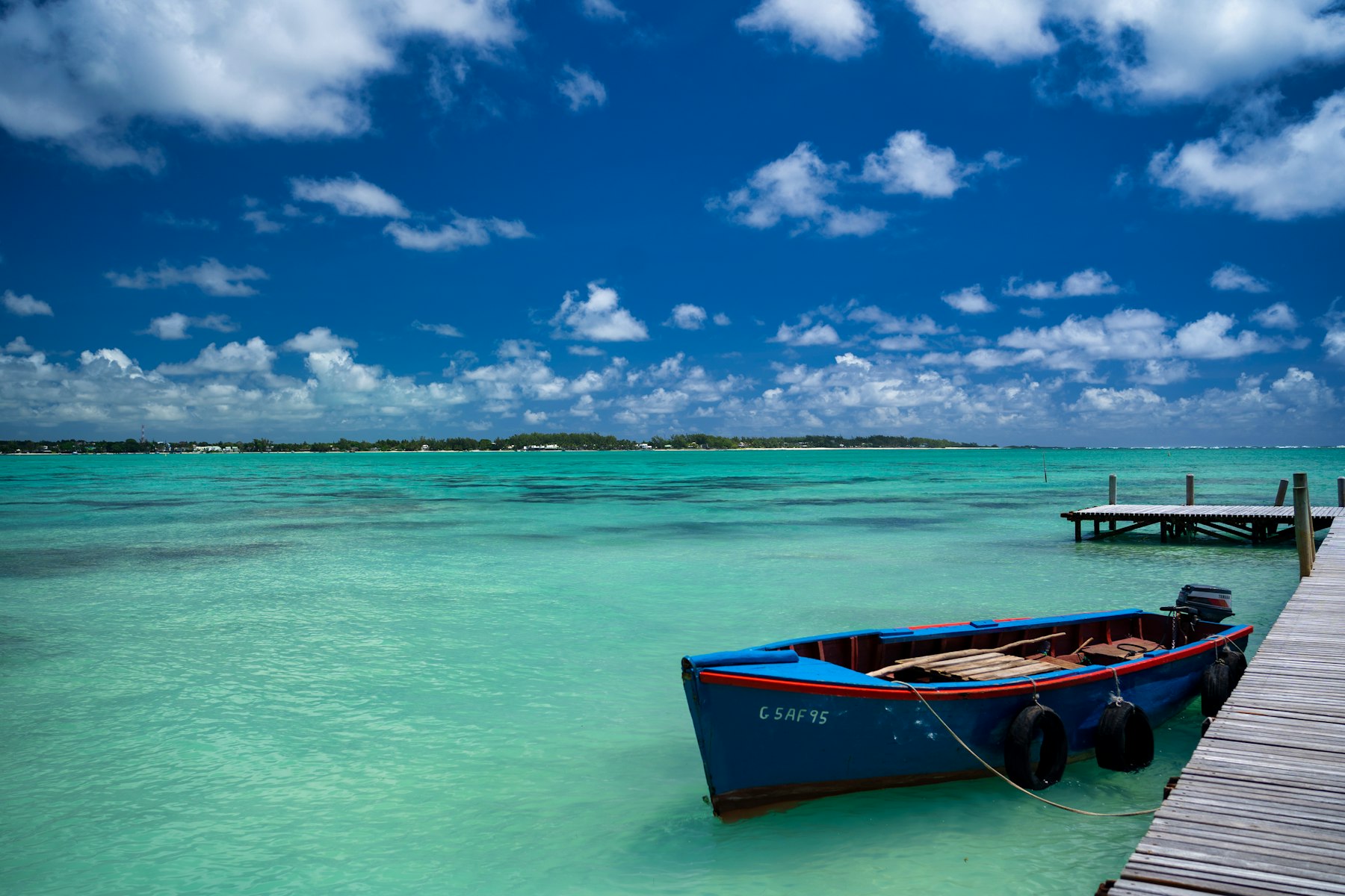 Wooden boat moored at a jetty over a turquoise lagoon